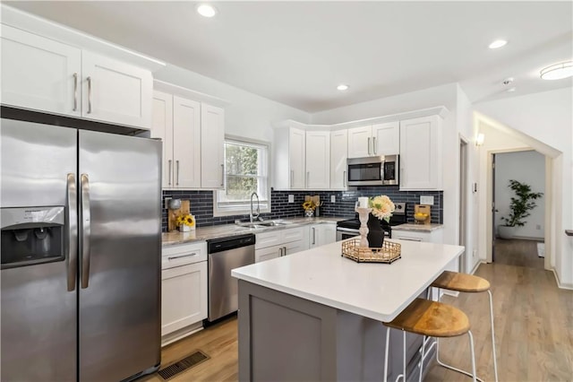 2206 Loring Ct, Decatur, GA 30032 - kitchen featuring a sink, stainless steel appliances, a kitchen bar, light countertops, and white cabinets