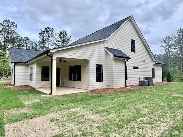 back of property with ceiling fan, a patio, a shingled roof, a lawn, and cooling unit