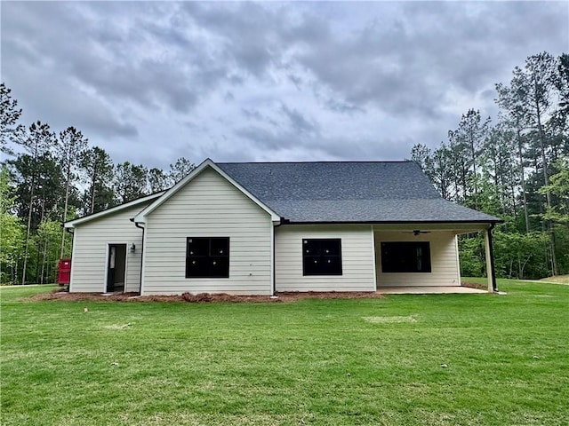 view of front of house featuring a front yard, ceiling fan, and roof with shingles