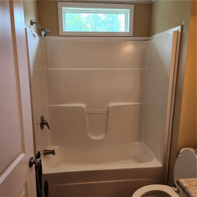 bathroom featuring a healthy amount of sunlight, bathing tub / shower combination, and toilet