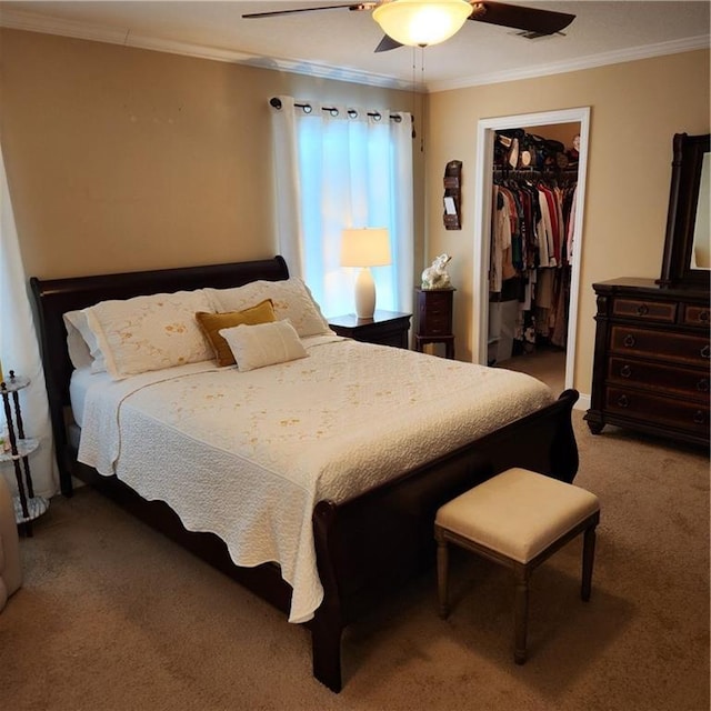 bedroom featuring a closet, ornamental molding, a walk in closet, ceiling fan, and carpet