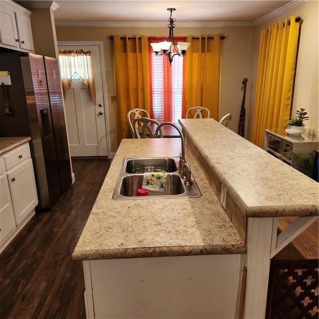 kitchen with crown molding, an island with sink, a sink, and fridge with ice dispenser