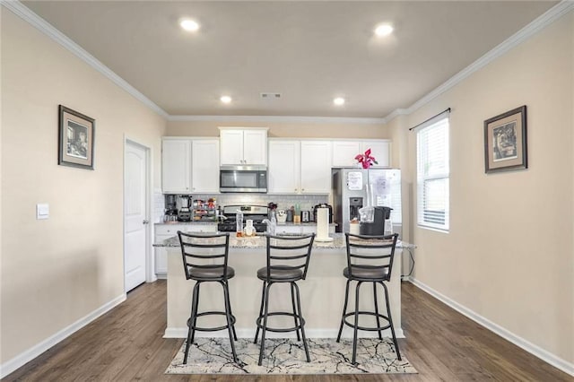 kitchen featuring a breakfast bar area, white cabinetry, stainless steel appliances, and a center island with sink