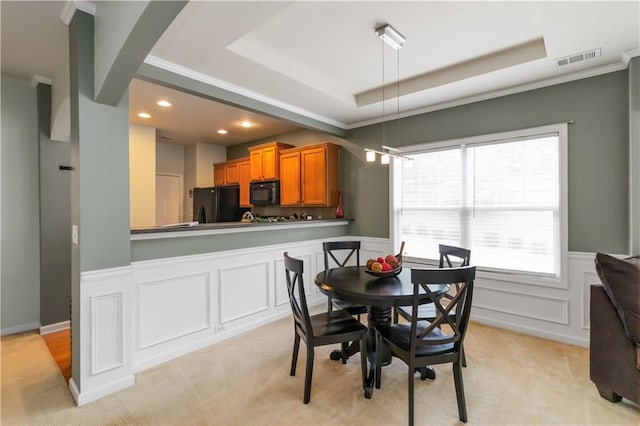 dining area with a raised ceiling, crown molding, a wainscoted wall, recessed lighting, and light carpet