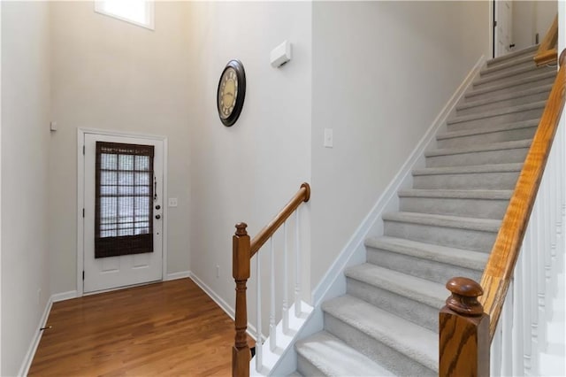 entryway with stairs, wood finished floors, and baseboards