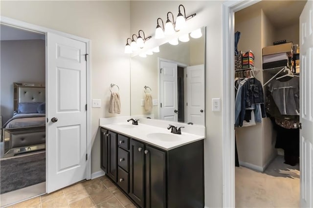 full bath featuring double vanity, ensuite bath, baseboards, and a walk in closet