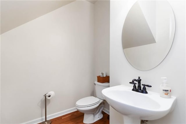 half bath with wood finished floors, a sink, toilet, and baseboards
