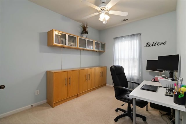 office featuring a ceiling fan, light colored carpet, and baseboards