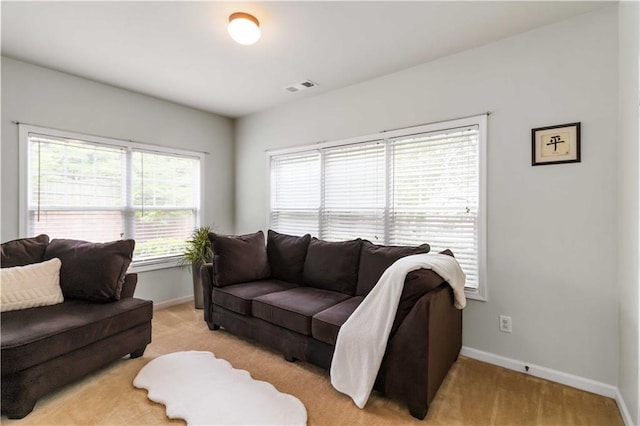 living area featuring light carpet and baseboards