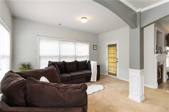 living room featuring arched walkways, a glass covered fireplace, light carpet, ornamental molding, and baseboards