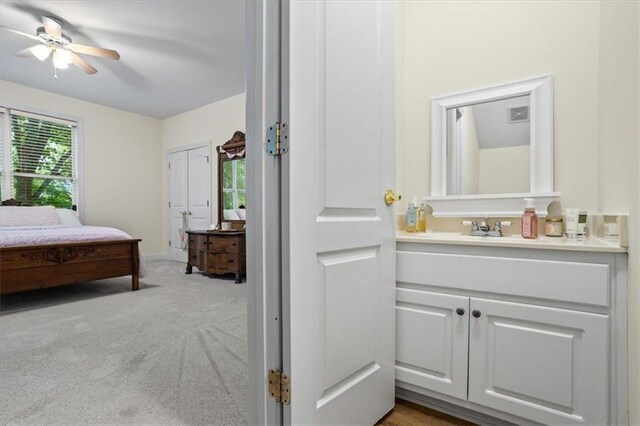 bedroom featuring ceiling fan, sink, and light carpet