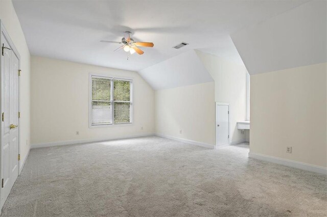 additional living space featuring vaulted ceiling, light colored carpet, and ceiling fan