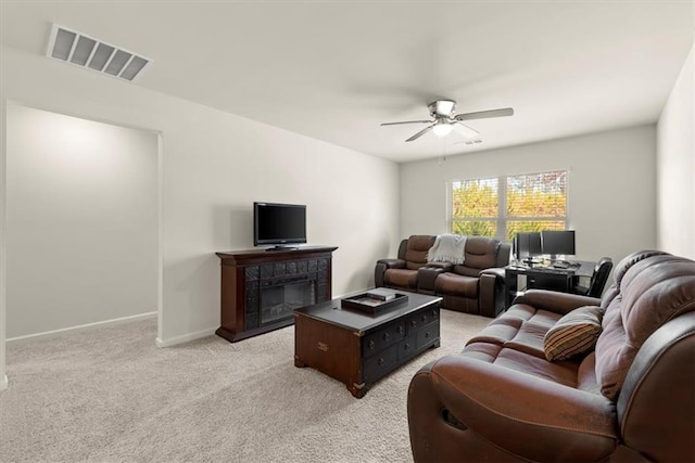 living room featuring visible vents, baseboards, light colored carpet, ceiling fan, and a fireplace