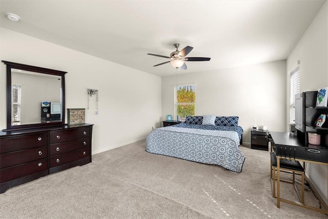 carpeted bedroom featuring ceiling fan, multiple windows, and baseboards