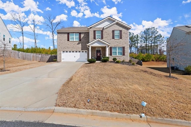 traditional-style home with an attached garage, fence, concrete driveway, and brick siding