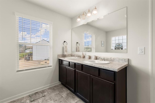 bathroom with double vanity, a sink, and baseboards