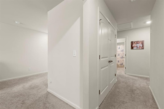 hallway with carpet floors, attic access, and baseboards