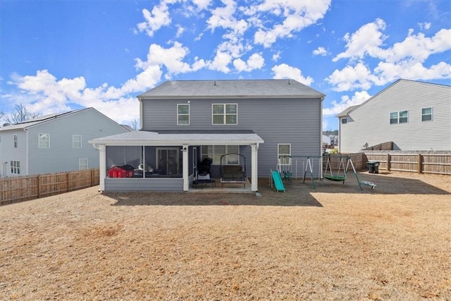 rear view of property with a patio area, a playground, a fenced backyard, and a sunroom