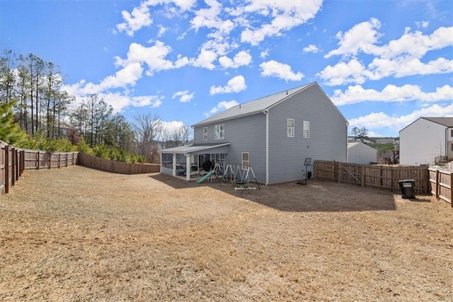 rear view of house featuring a fenced backyard and a sunroom