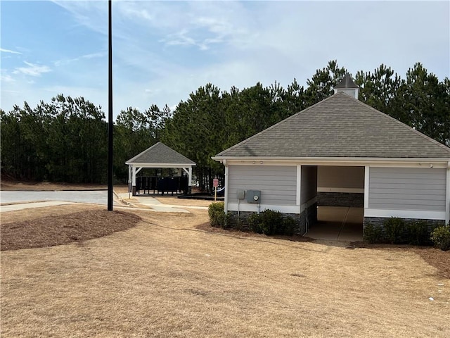 exterior space with a shingled roof and a gazebo