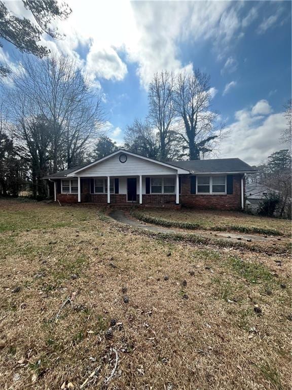 view of front of property with a porch, a front yard, and brick siding