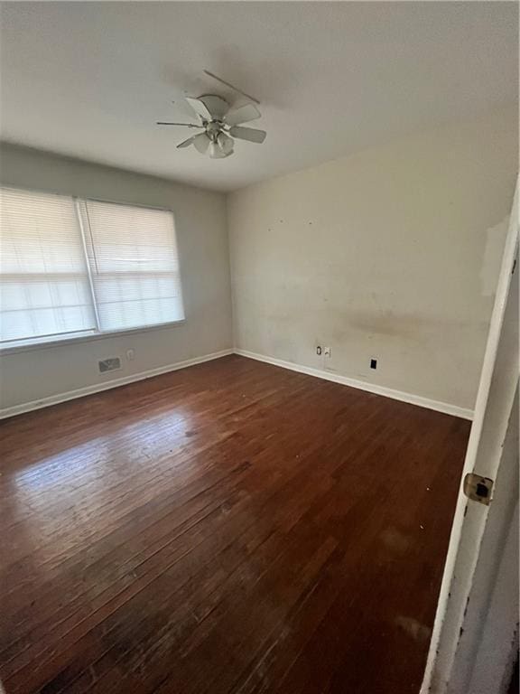 spare room featuring ceiling fan, baseboards, and dark wood finished floors