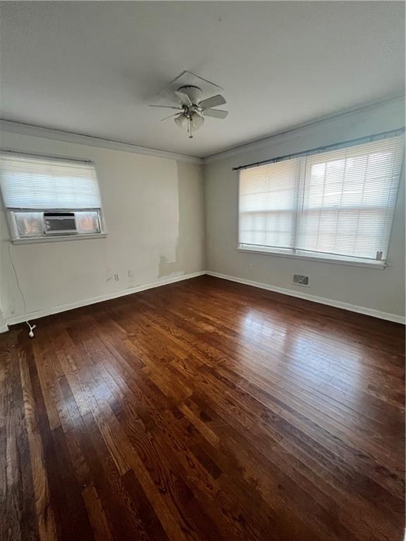 empty room with wood finished floors, plenty of natural light, cooling unit, and crown molding