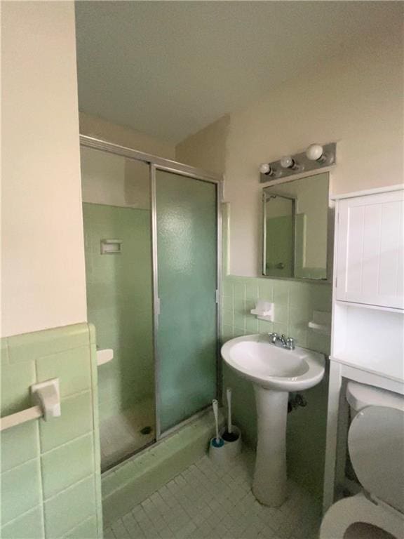 full bathroom featuring a stall shower, wainscoting, tile walls, and toilet