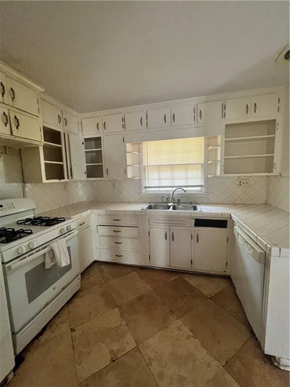 kitchen with tile countertops, open shelves, tasteful backsplash, a sink, and white appliances