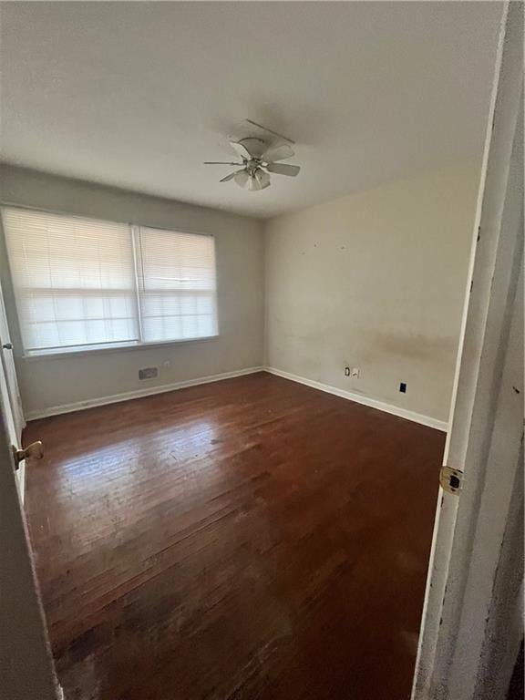 empty room with dark wood-style floors, ceiling fan, and baseboards