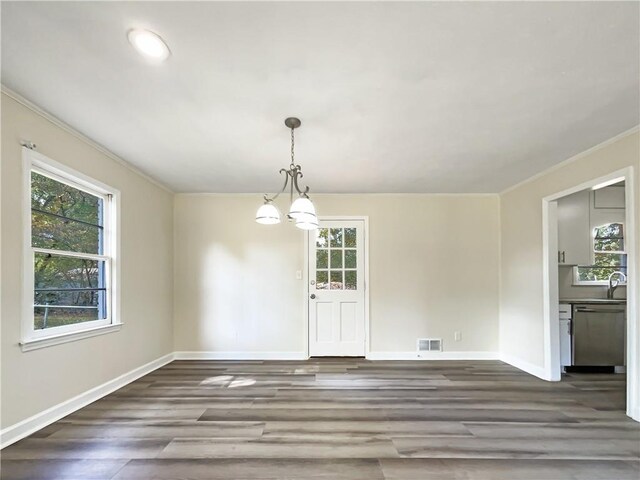 unfurnished dining area with ornamental molding, a chandelier, sink, and dark hardwood / wood-style floors