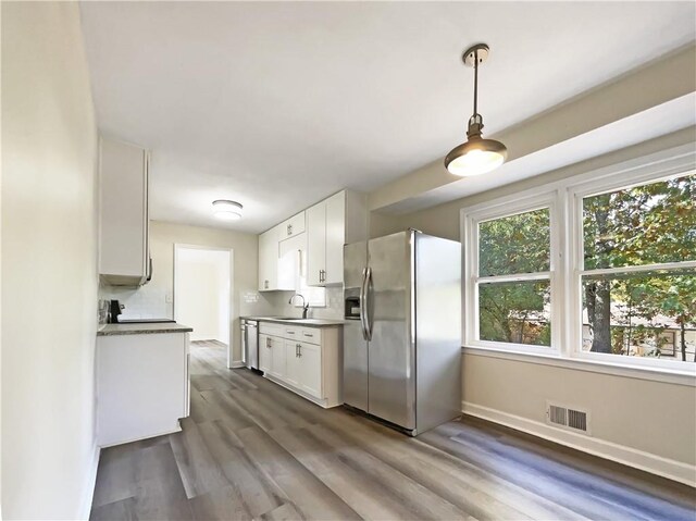 kitchen with stainless steel appliances, white cabinetry, dark hardwood / wood-style flooring, hanging light fixtures, and sink