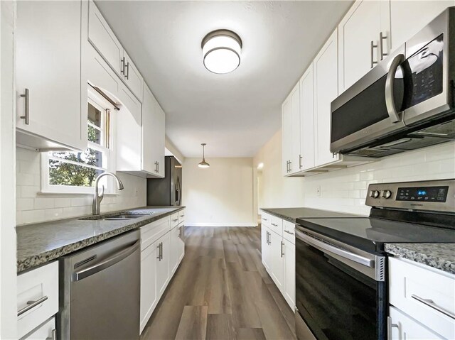 kitchen with white cabinetry, appliances with stainless steel finishes, pendant lighting, and dark hardwood / wood-style flooring