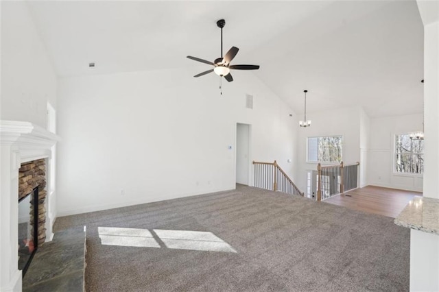 unfurnished living room featuring visible vents, a fireplace, high vaulted ceiling, ceiling fan with notable chandelier, and carpet
