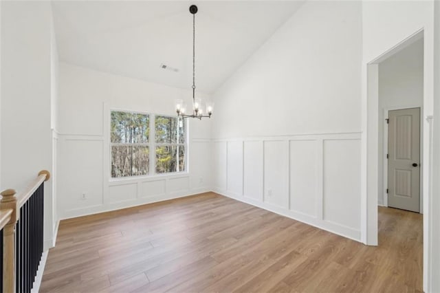 unfurnished dining area with light wood-style floors, a chandelier, and a decorative wall