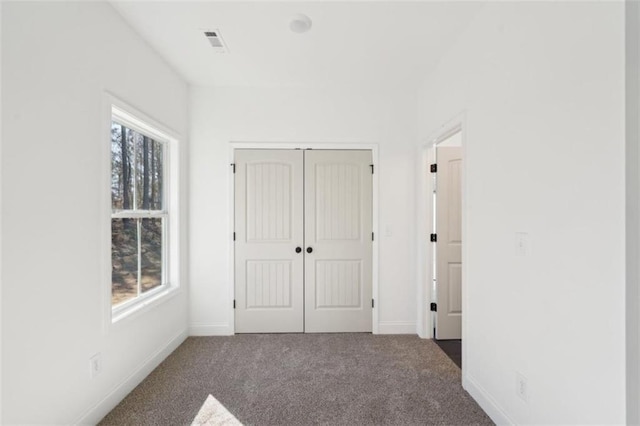 unfurnished bedroom featuring visible vents, carpet, baseboards, and a closet
