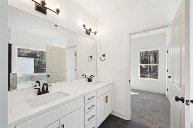 full bath featuring double vanity, baseboards, and a sink