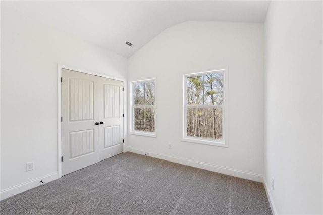 unfurnished bedroom with carpet, baseboards, lofted ceiling, visible vents, and a closet