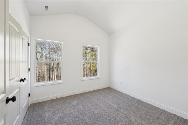 carpeted spare room featuring baseboards, visible vents, and lofted ceiling