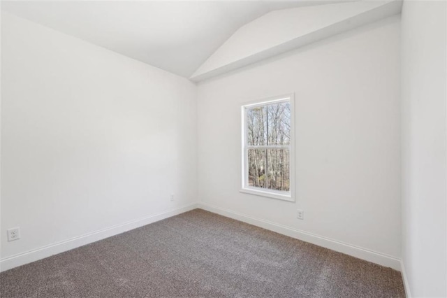 carpeted empty room featuring baseboards and vaulted ceiling