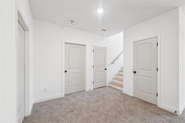 unfurnished bedroom featuring baseboards, carpet flooring, multiple closets, and visible vents