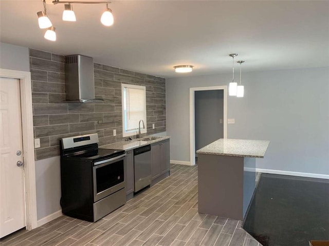 kitchen with sink, hanging light fixtures, wall chimney range hood, light hardwood / wood-style flooring, and appliances with stainless steel finishes