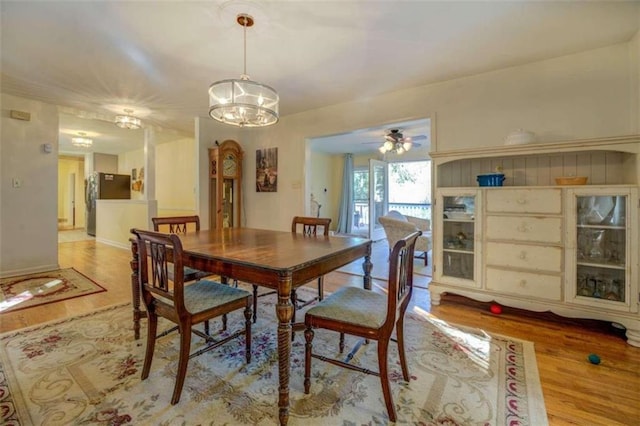 dining area with ceiling fan with notable chandelier and light hardwood / wood-style floors