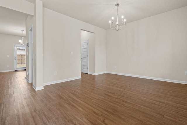 spare room featuring a chandelier and dark hardwood / wood-style floors