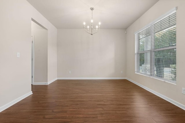 unfurnished room with a notable chandelier and dark hardwood / wood-style floors