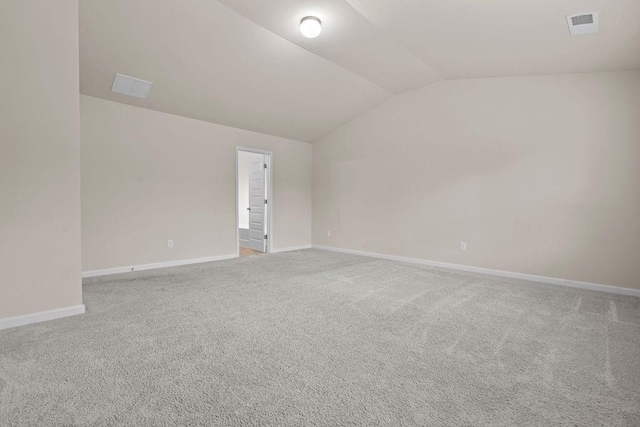 carpeted spare room featuring vaulted ceiling