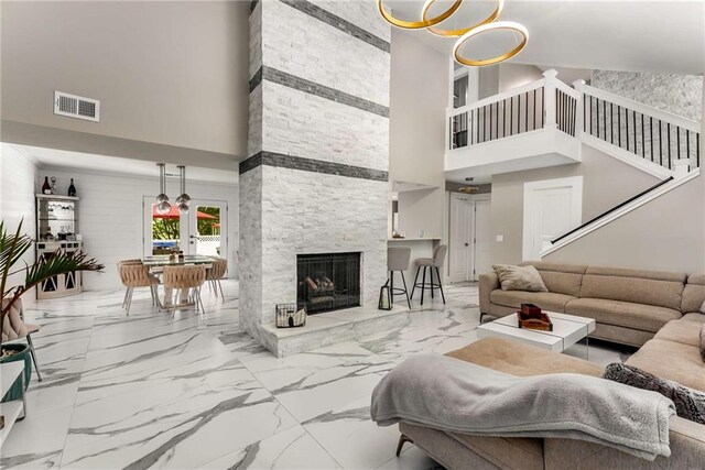 tiled living room with a notable chandelier, a stone fireplace, and a high ceiling