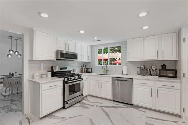 kitchen with light tile patterned flooring, appliances with stainless steel finishes, sink, and white cabinets