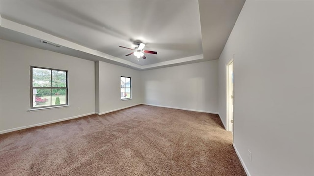 spare room featuring carpet flooring, baseboards, visible vents, a raised ceiling, and a ceiling fan