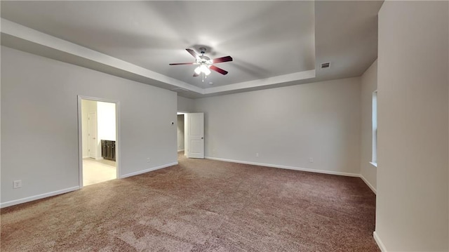 carpeted empty room with baseboards, visible vents, ceiling fan, and a tray ceiling
